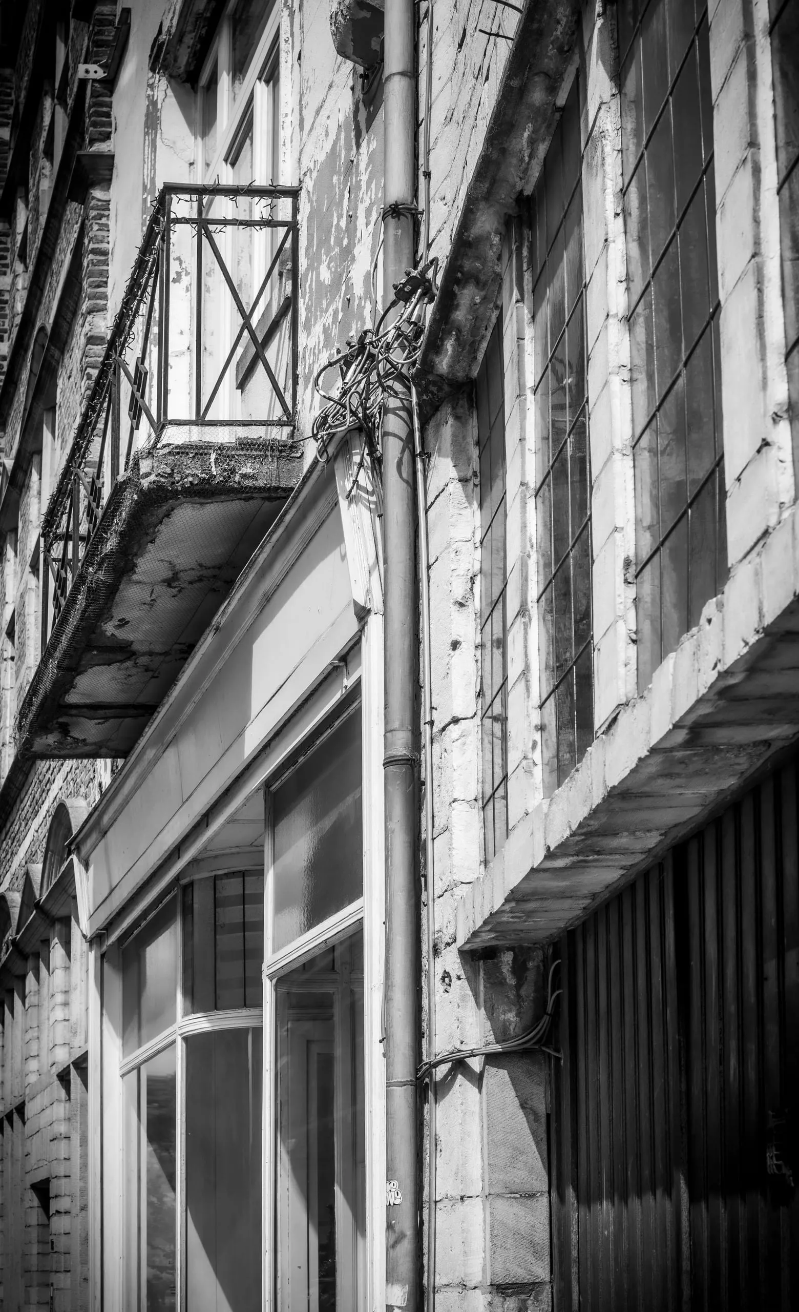 Verweerde gevel met een smeedijzeren balkon, in zwart-wit