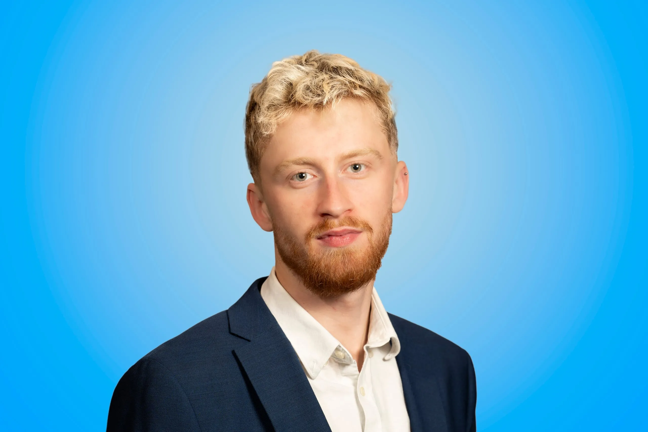 Hoofd-en-schouderportret van een man in marineblauw pak op een blauwe achtergrond