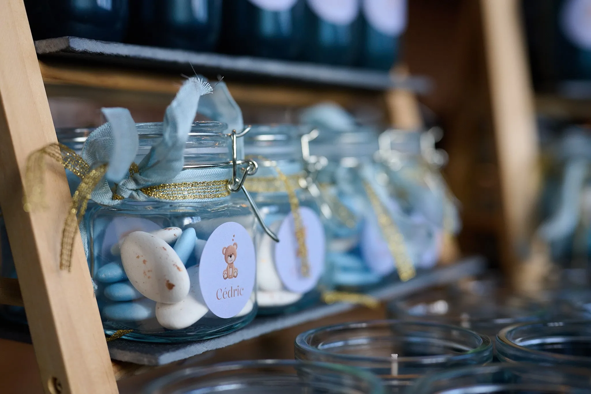 Glazen potjes met blauwe suikeramandelen en een strikje op een houten rek