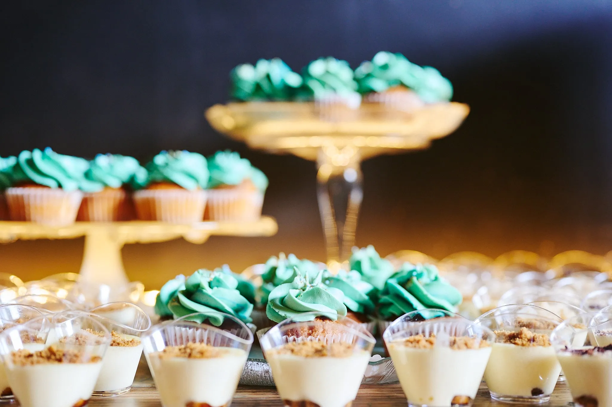 Cupcakes met mintgroene topping en dessertglaasjes op etagères
