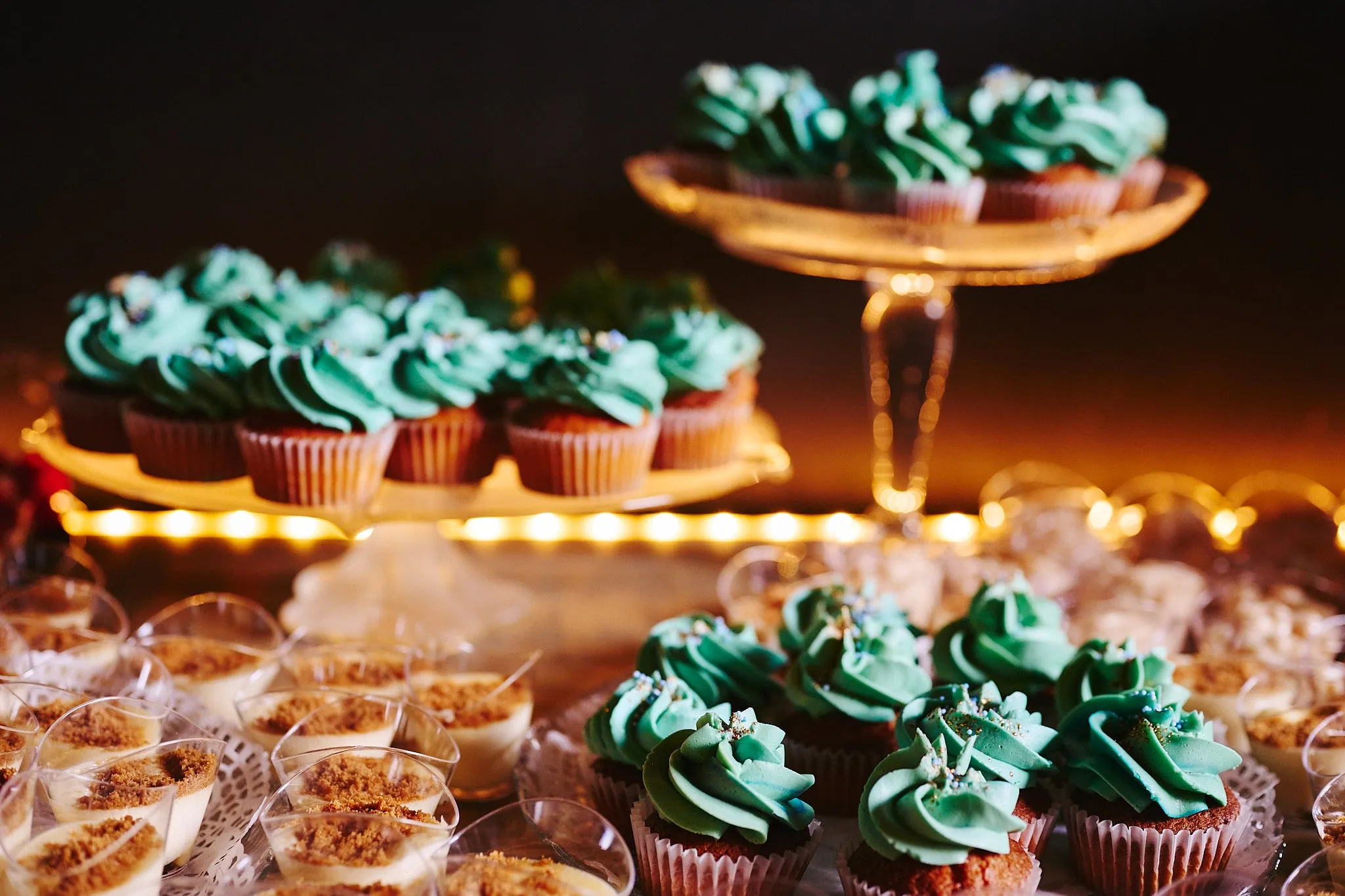 Warm verlichte dessertbuffet met cupcakes en dessertglaasjes