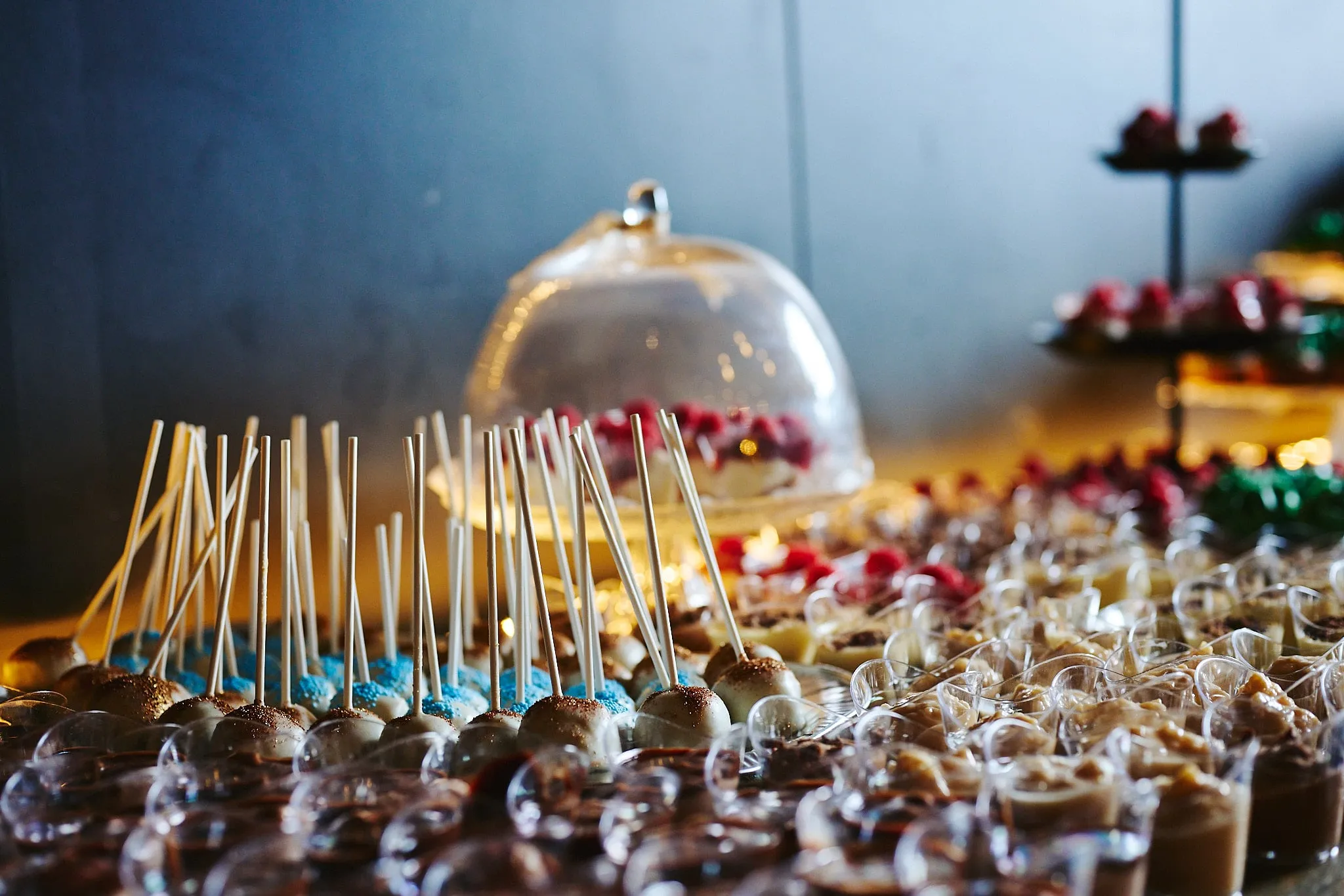Buffet met cakepops en dessertglaasjes onder een glazen stolp