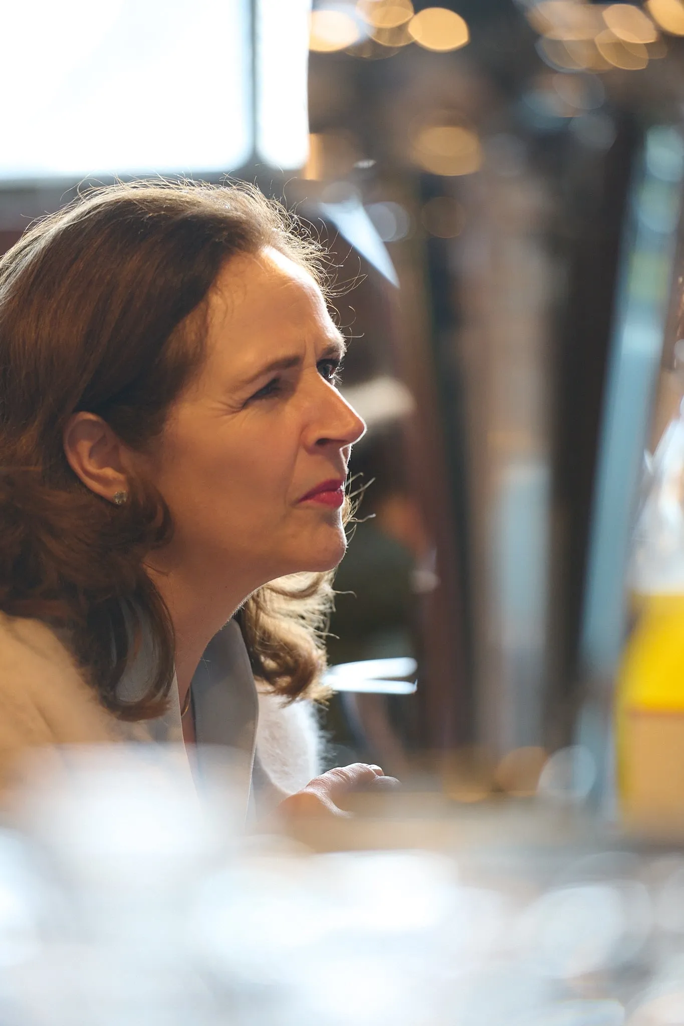 Profielportret van een vrouw in gesprek, met warme lichtvlekken op de achtergrond