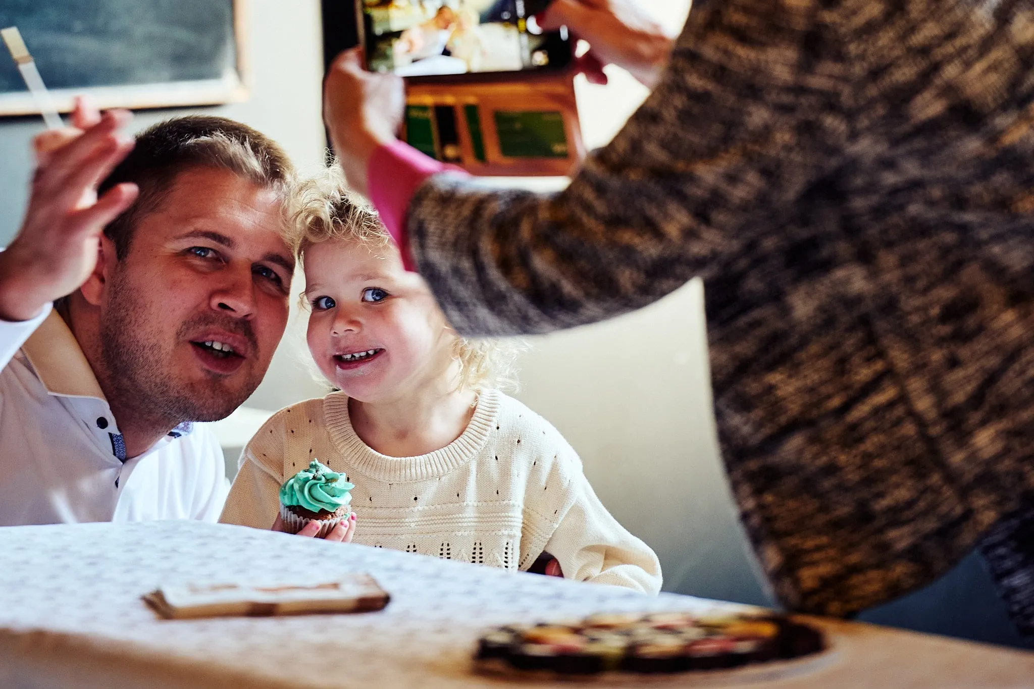 Vader en peuter lachen terwijl iemand een foto neemt met een telefoon