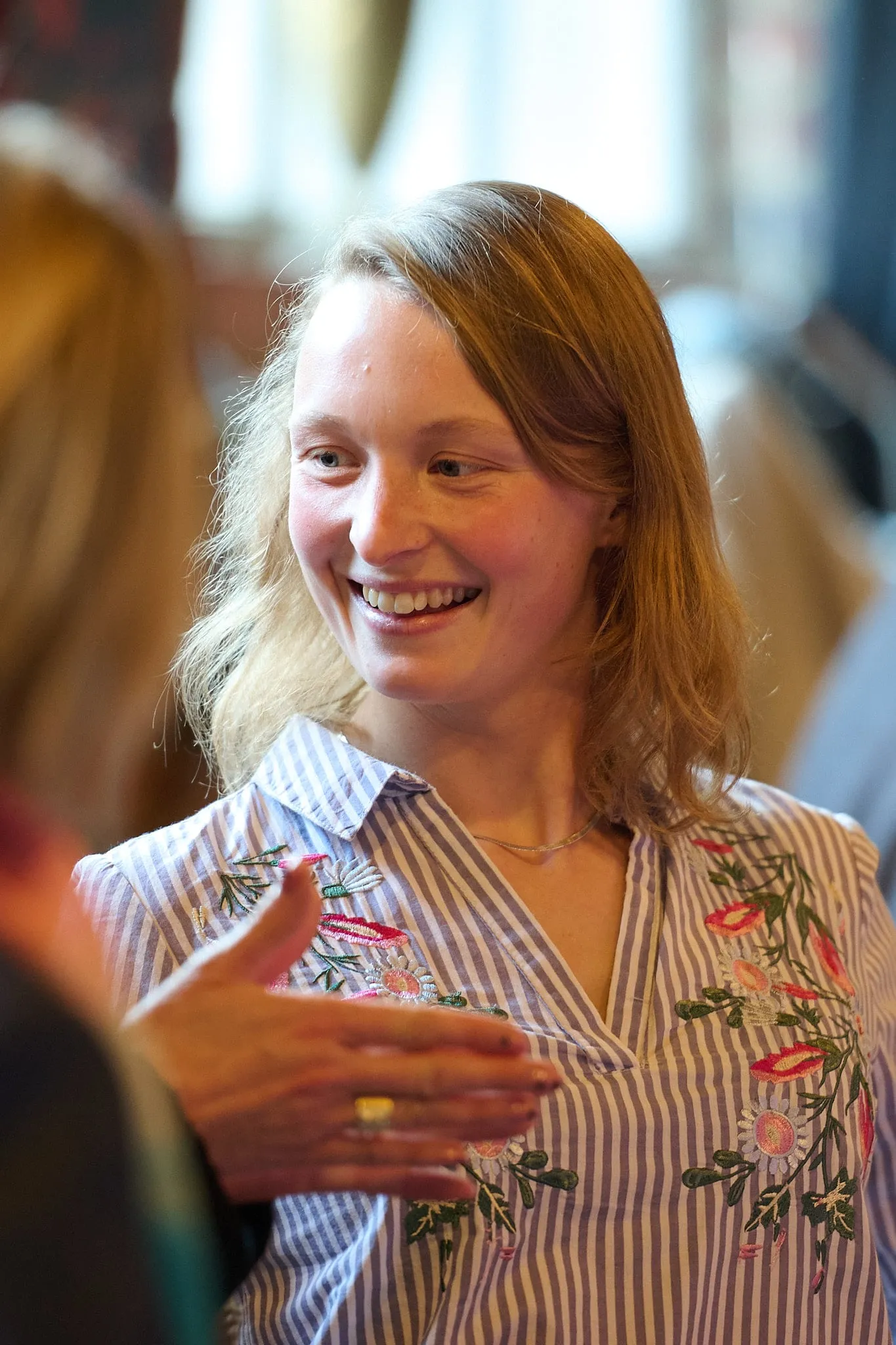 Lachende jonge vrouw in gestreepte blouse in gesprek