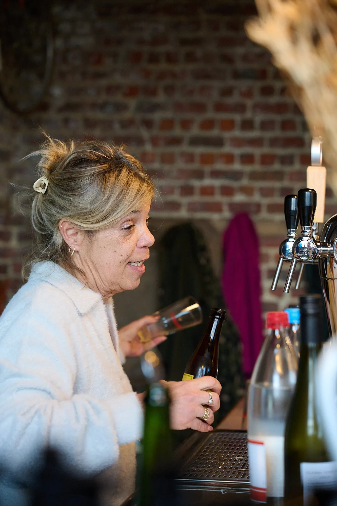 Vrouw met blond haar schenkt iets in aan de bar