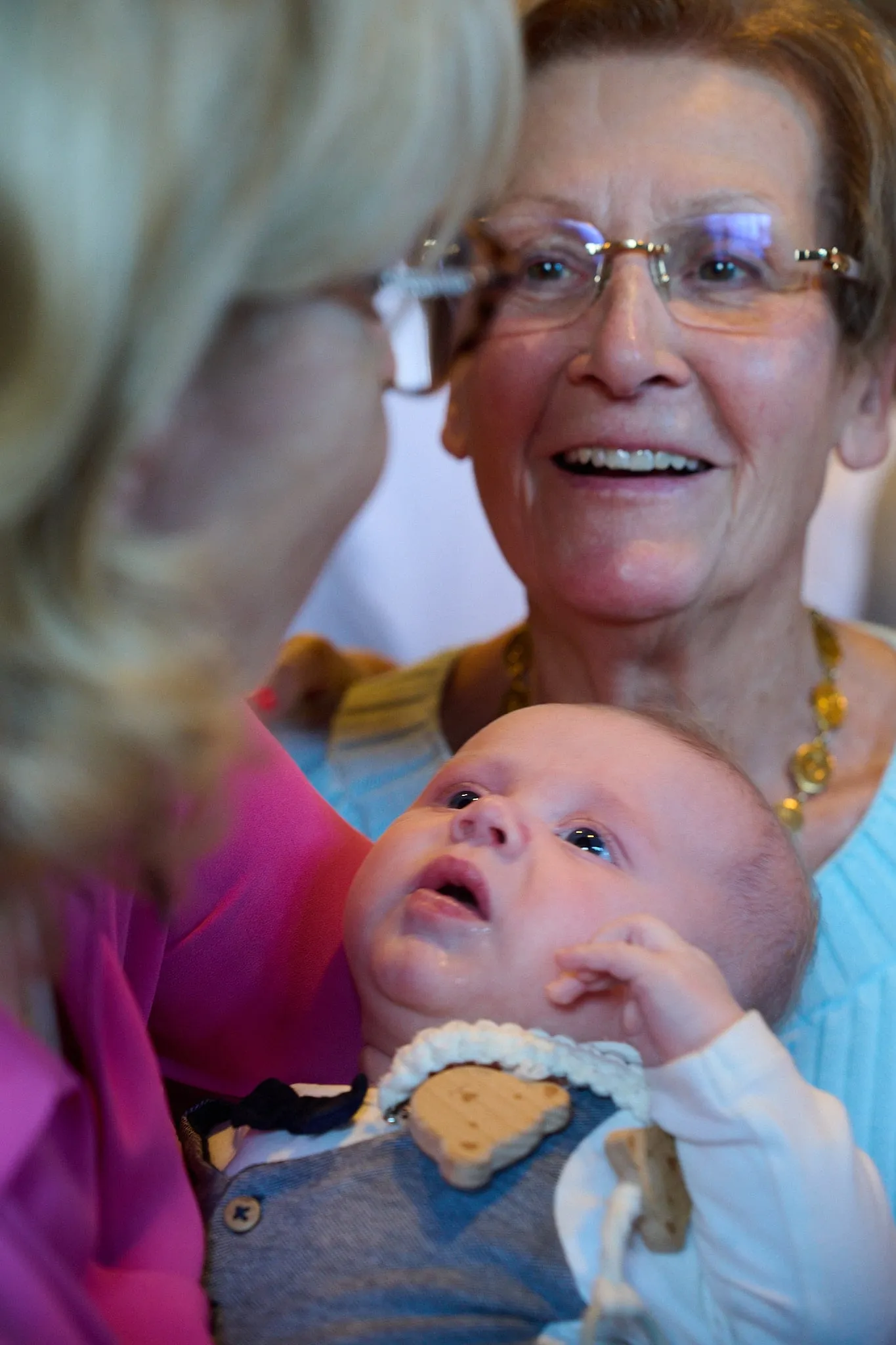 Grootmoeder met bril glimlacht naar een baby in de armen