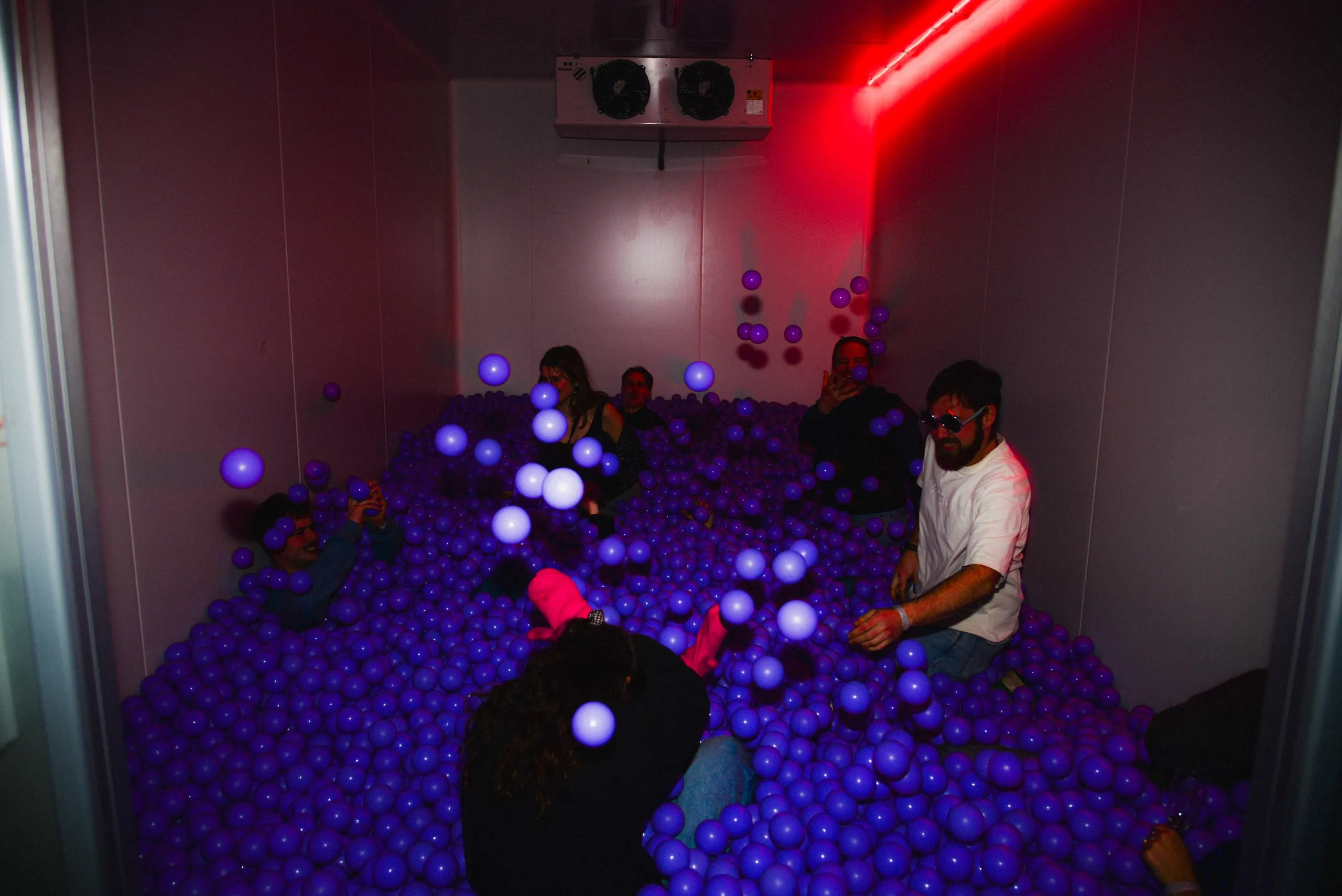 Ballenbad met paarse ballen in een ruimte met rood neonlicht