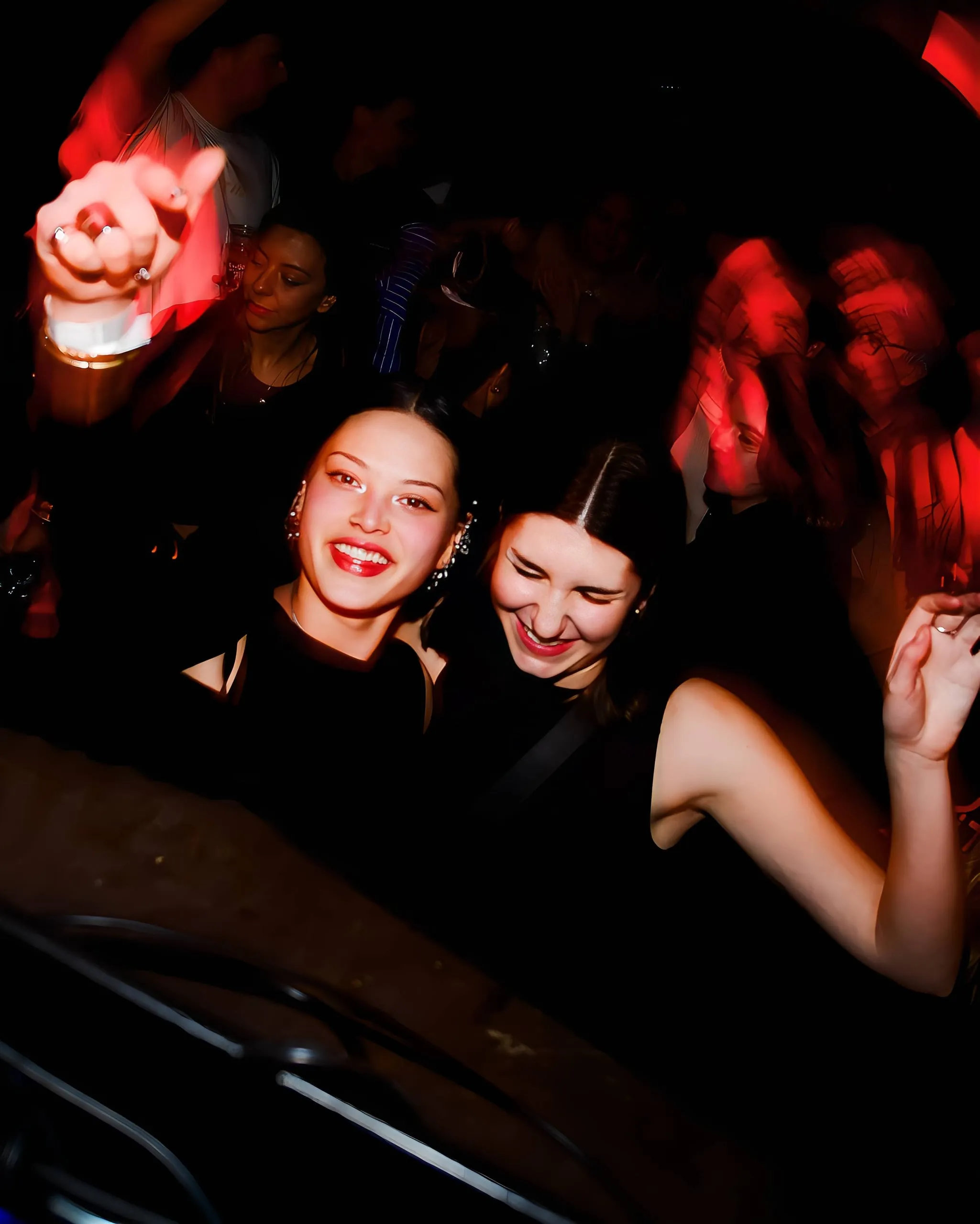 Twee lachende vrouwen op een druk feest, met bewegingsonscherpte