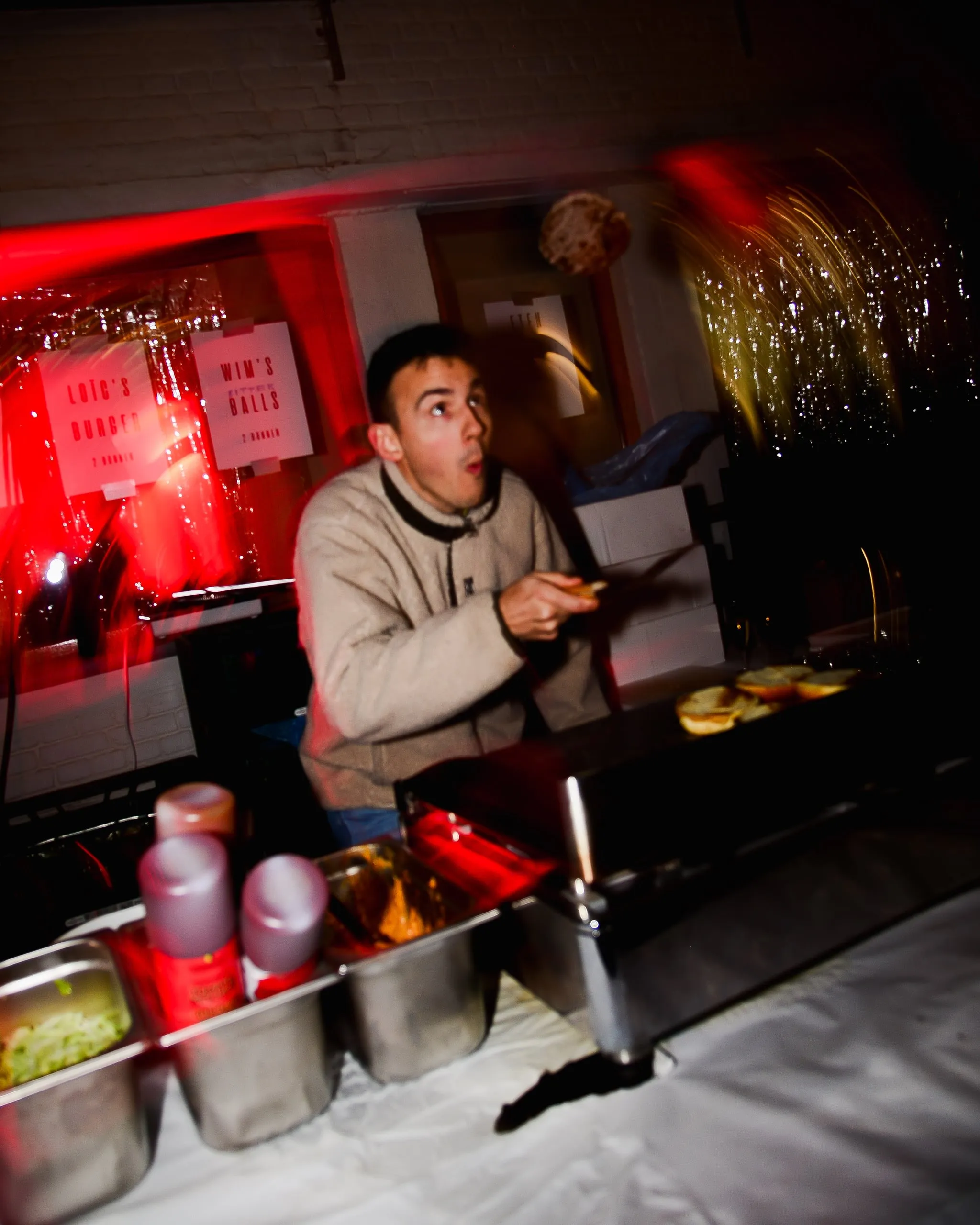 Man achter een foodstand kijkt verbaasd in de camera, in rood licht