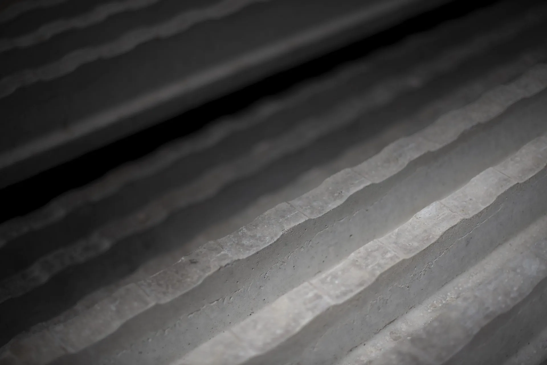 Close-up van golvende betonnen trappen in zwart-wit, schuin gefotografeerd