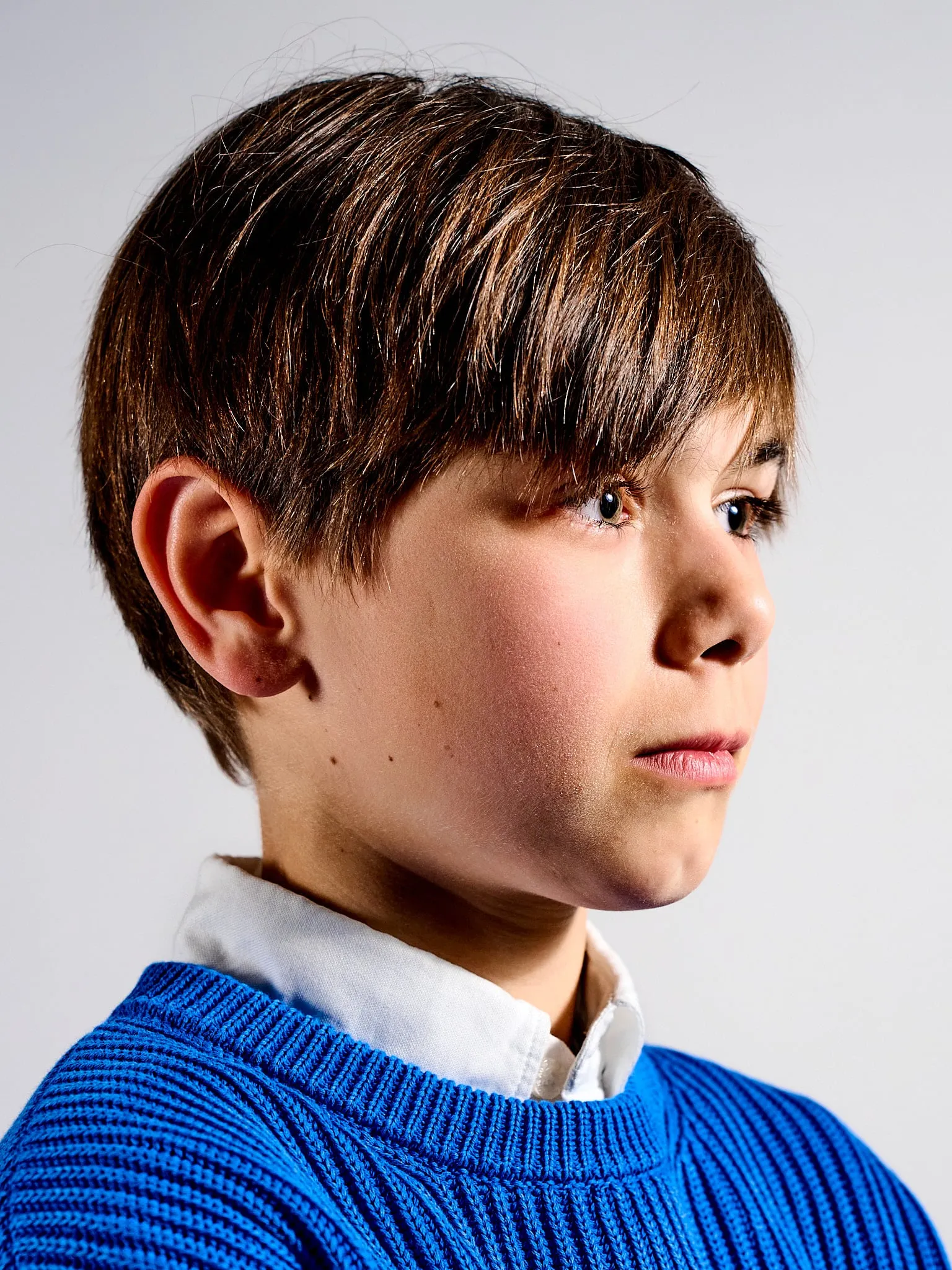 Portret van een jongen in een blauwe trui die opzij kijkt