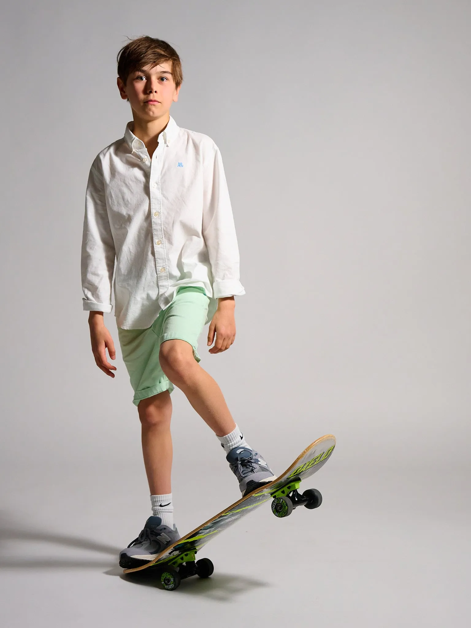 Jongen in wit hemd en groene short met een skateboard