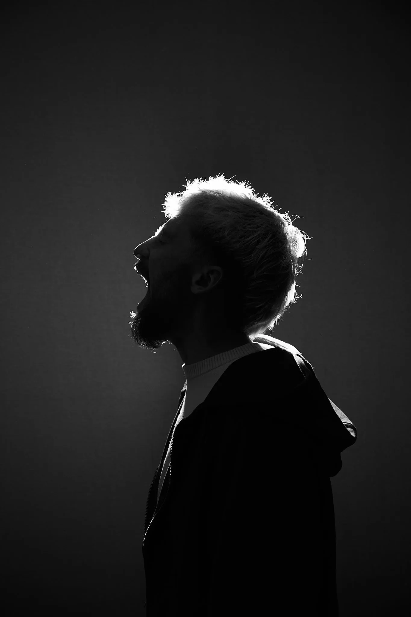 Silhouet in profiel met sterk tegenlicht op het haar, in zwart-wit