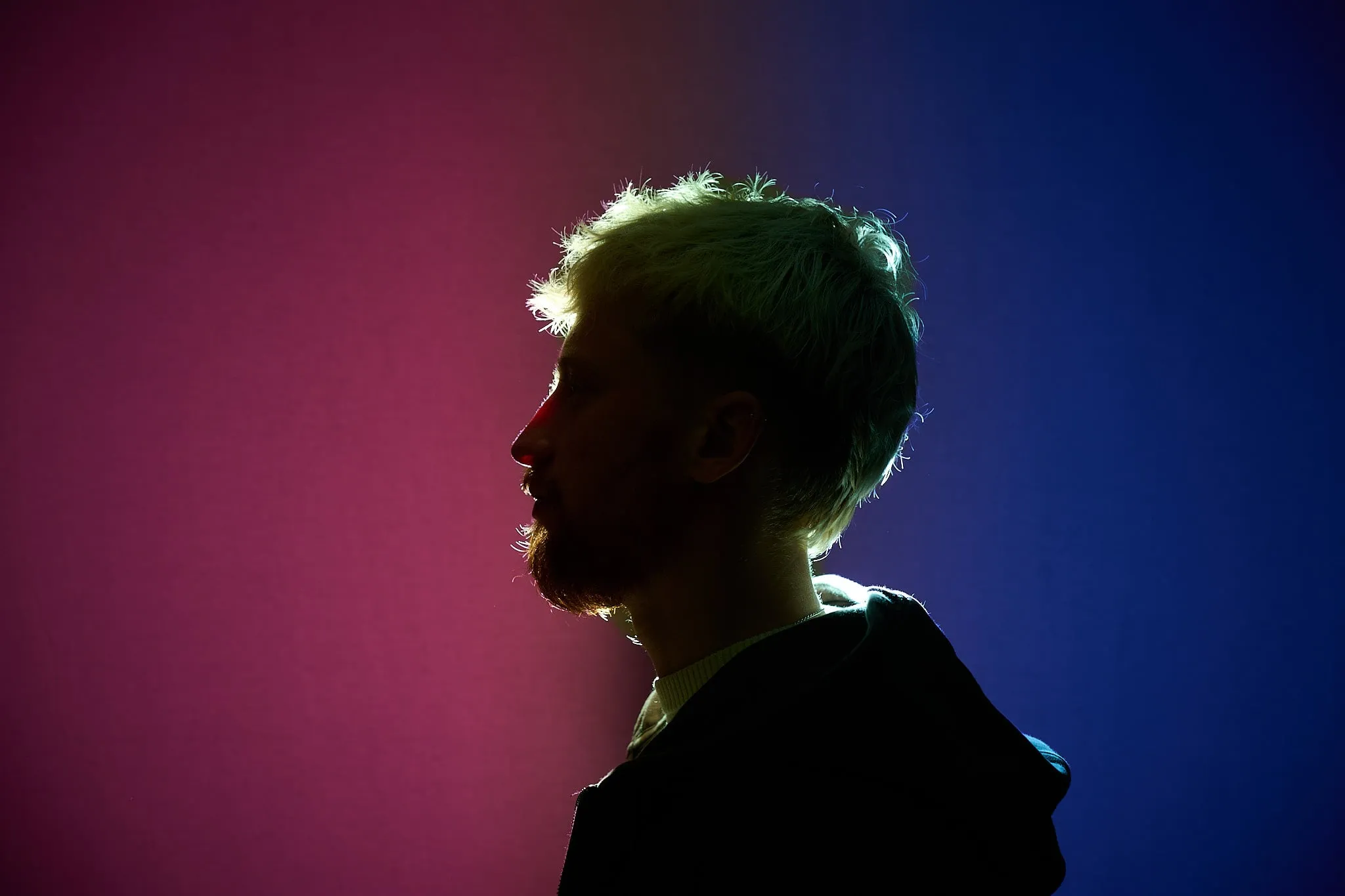 Profiel van een man tegen een roze en blauwe lichtgekleurde achtergrond