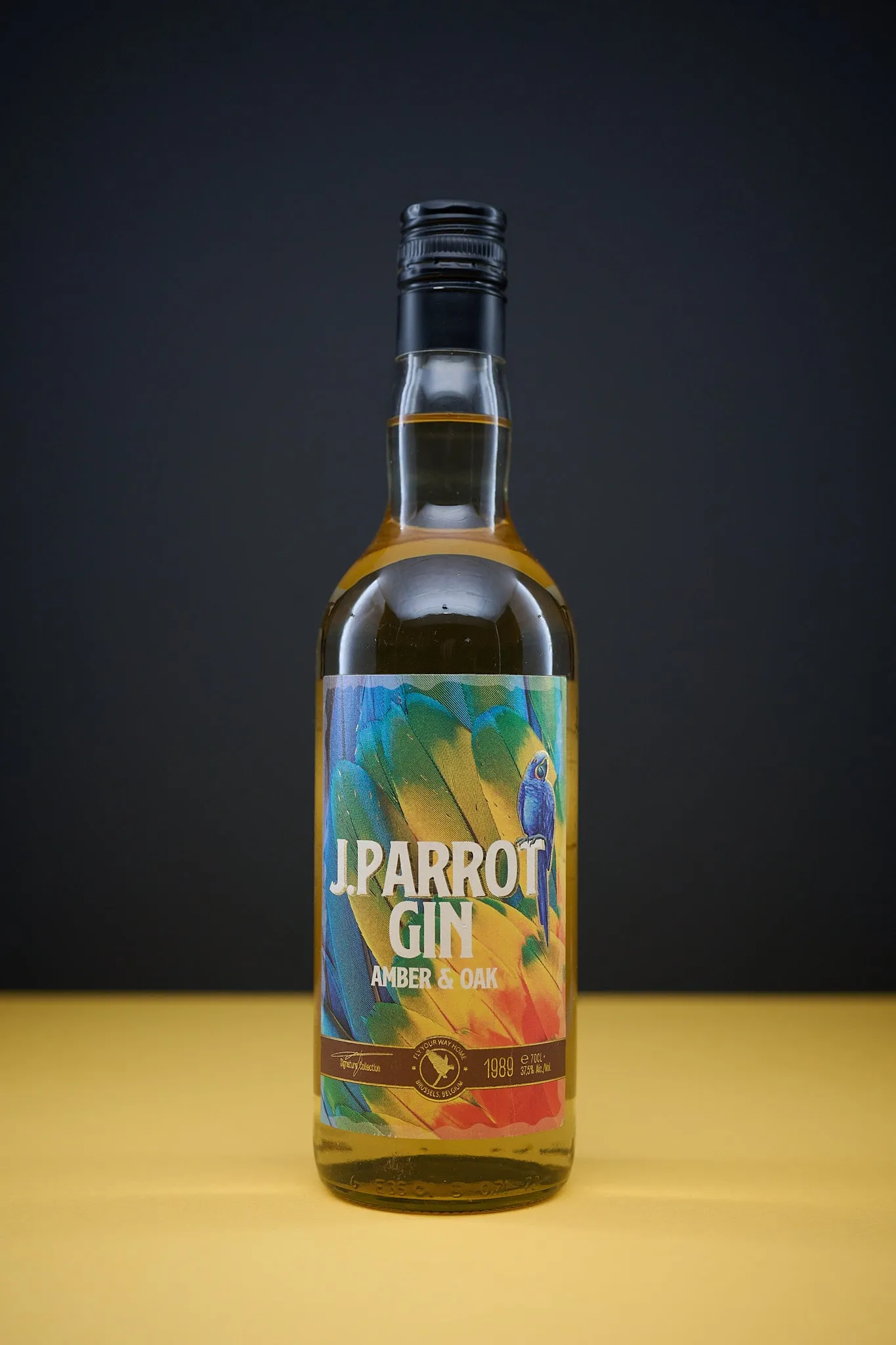 Fles J. Parrot Gin Amber & Oak op een gele ondergrond