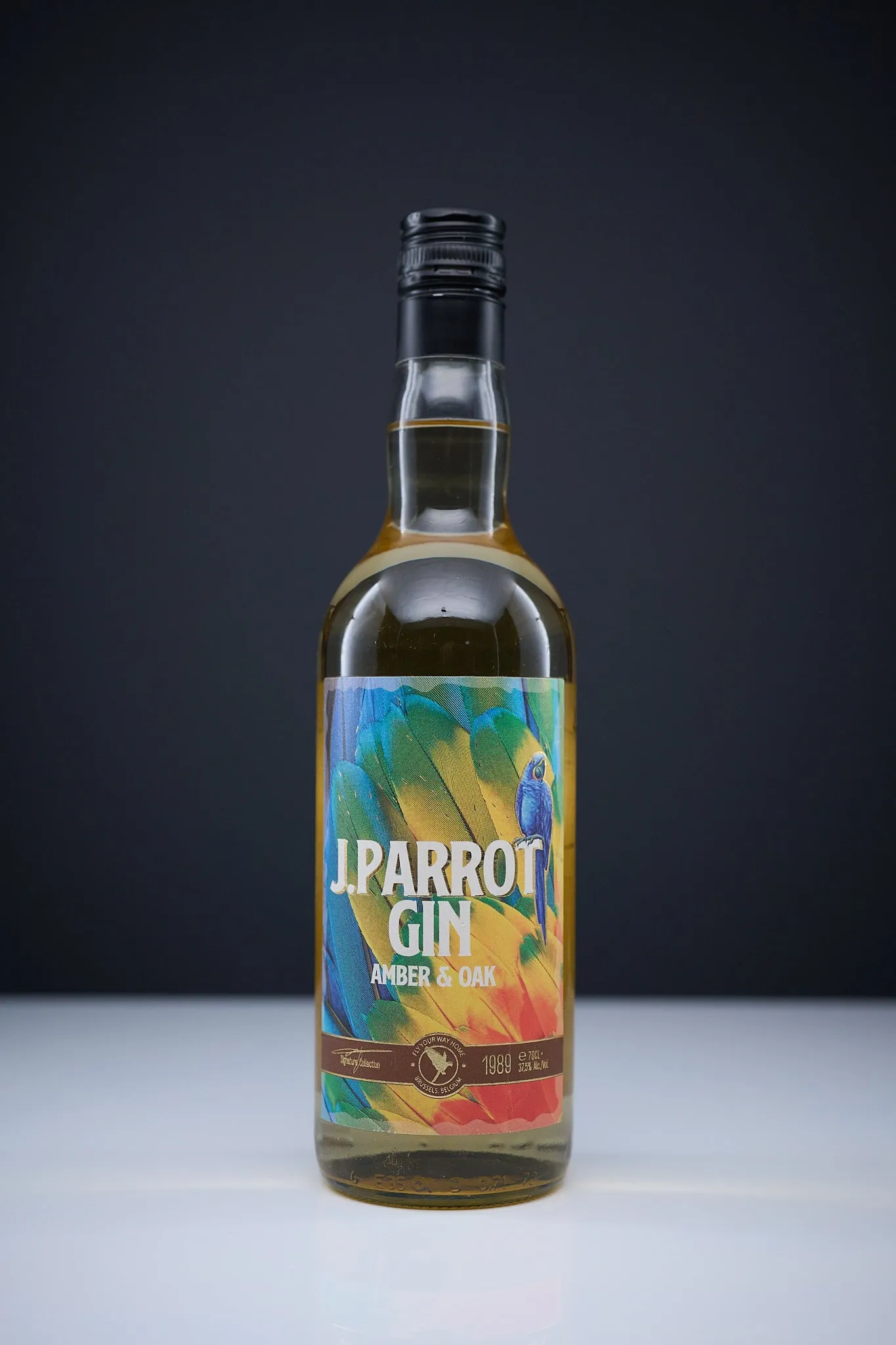 Fles J. Parrot Gin Amber & Oak voor een donkere achtergrond