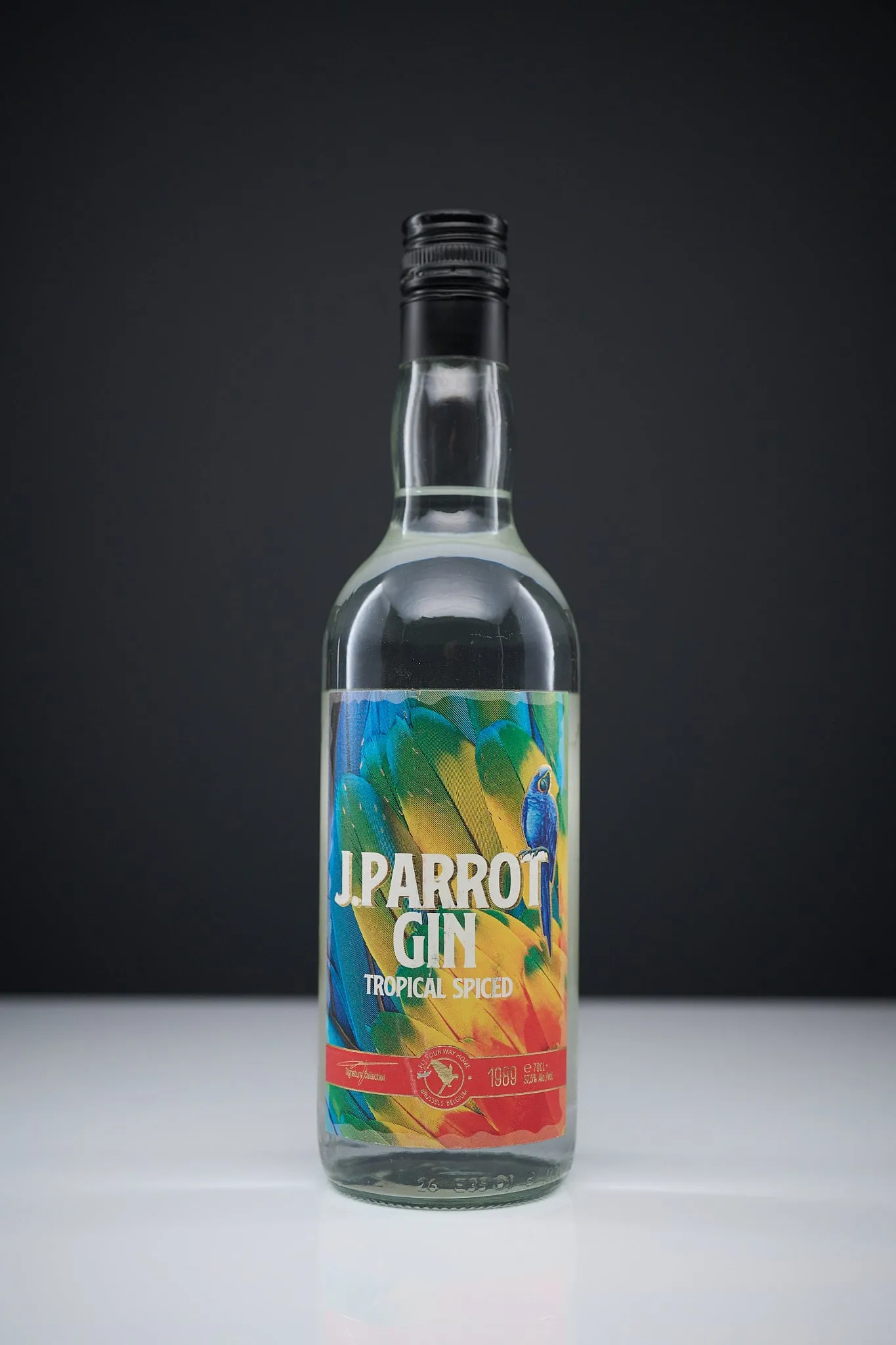 Fles J. Parrot Gin Tropical Spiced voor een donkere achtergrond