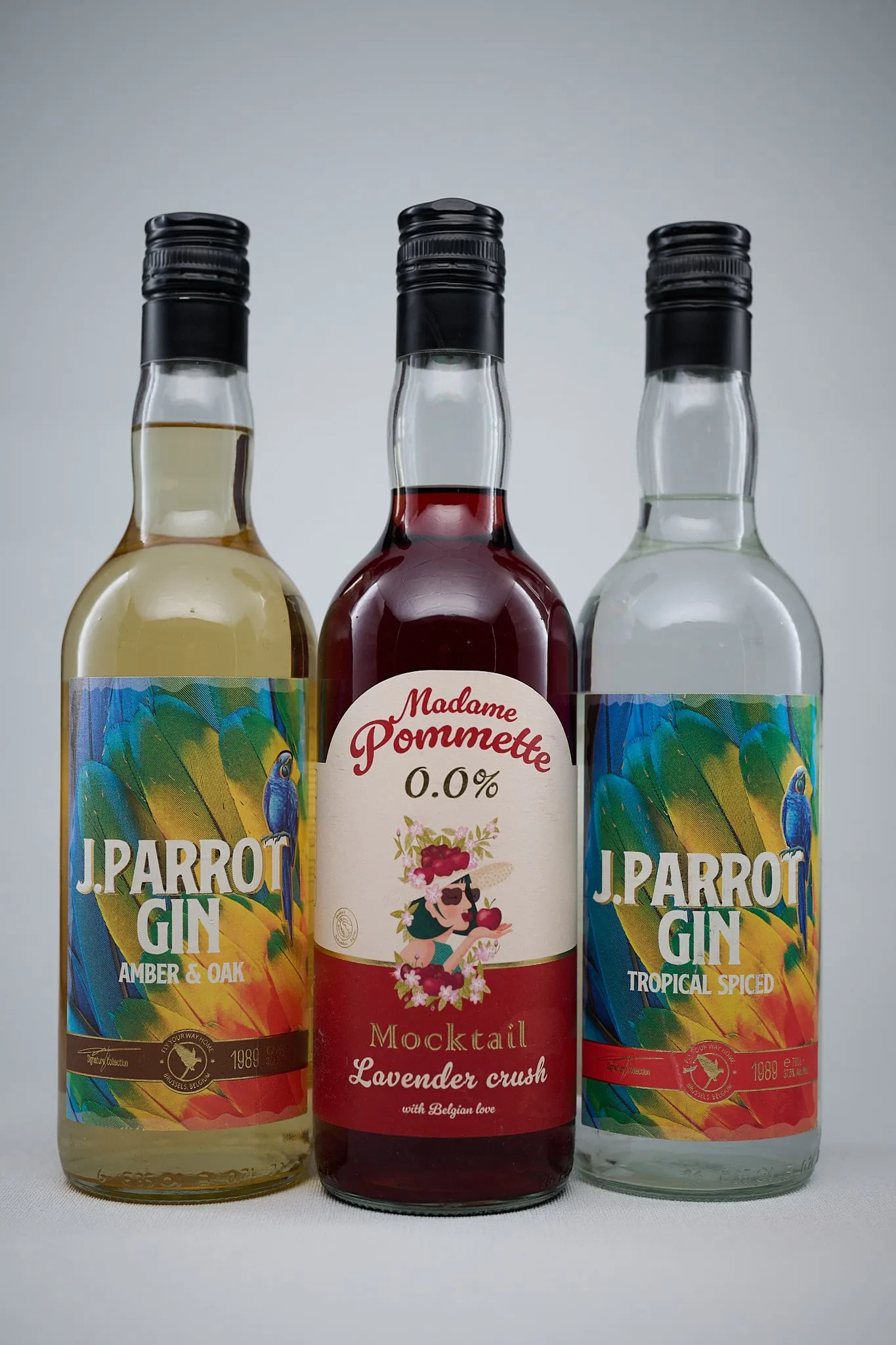 Drie flessen J. Parrot Gin en Madame Pommette tegen een lichtgrijze achtergrond